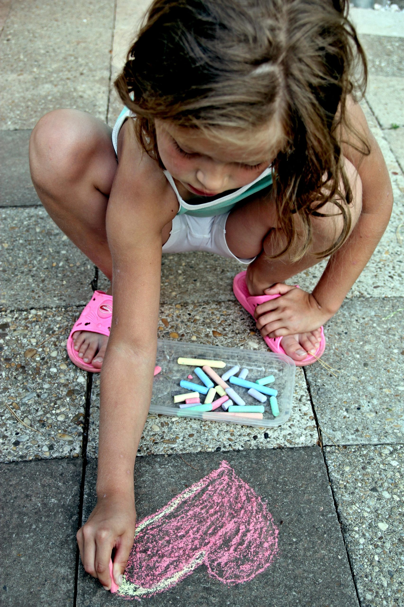 child creating a new picture on the sidewalk